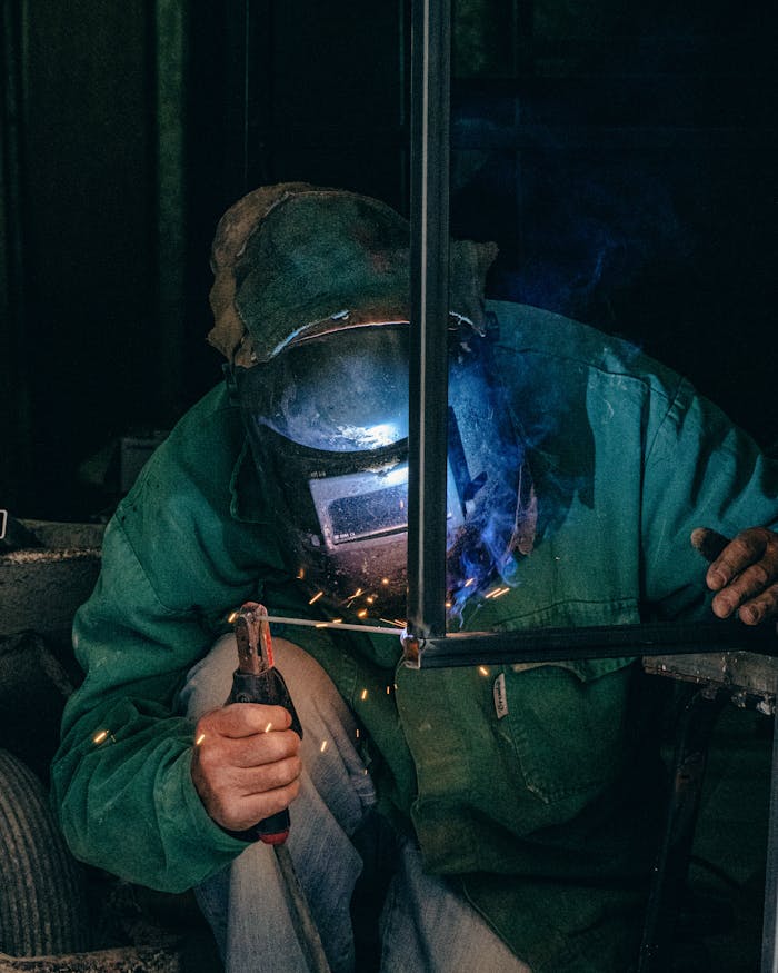 gallery-3 Welder using equipment in a Mellieħa workshop, garbed in safety gear with welding sparks.