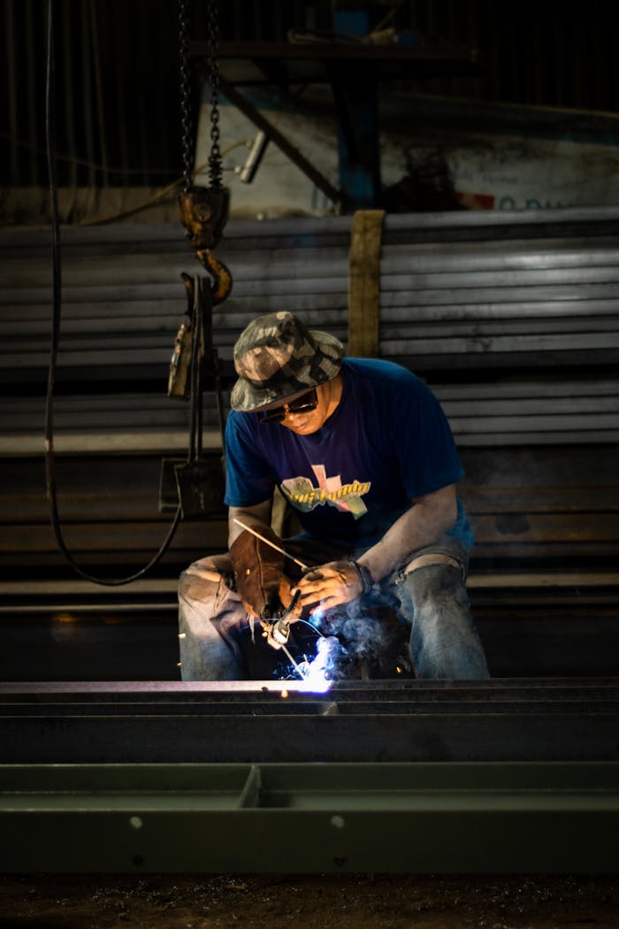 our-experience A man welding steel in an industrial setting, focused on his work.