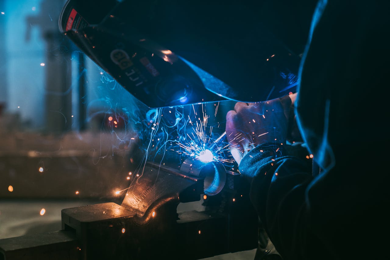 hero-img-02 Close-up of a welder working with sparks flying, showcasing industrial craft in Paris.
