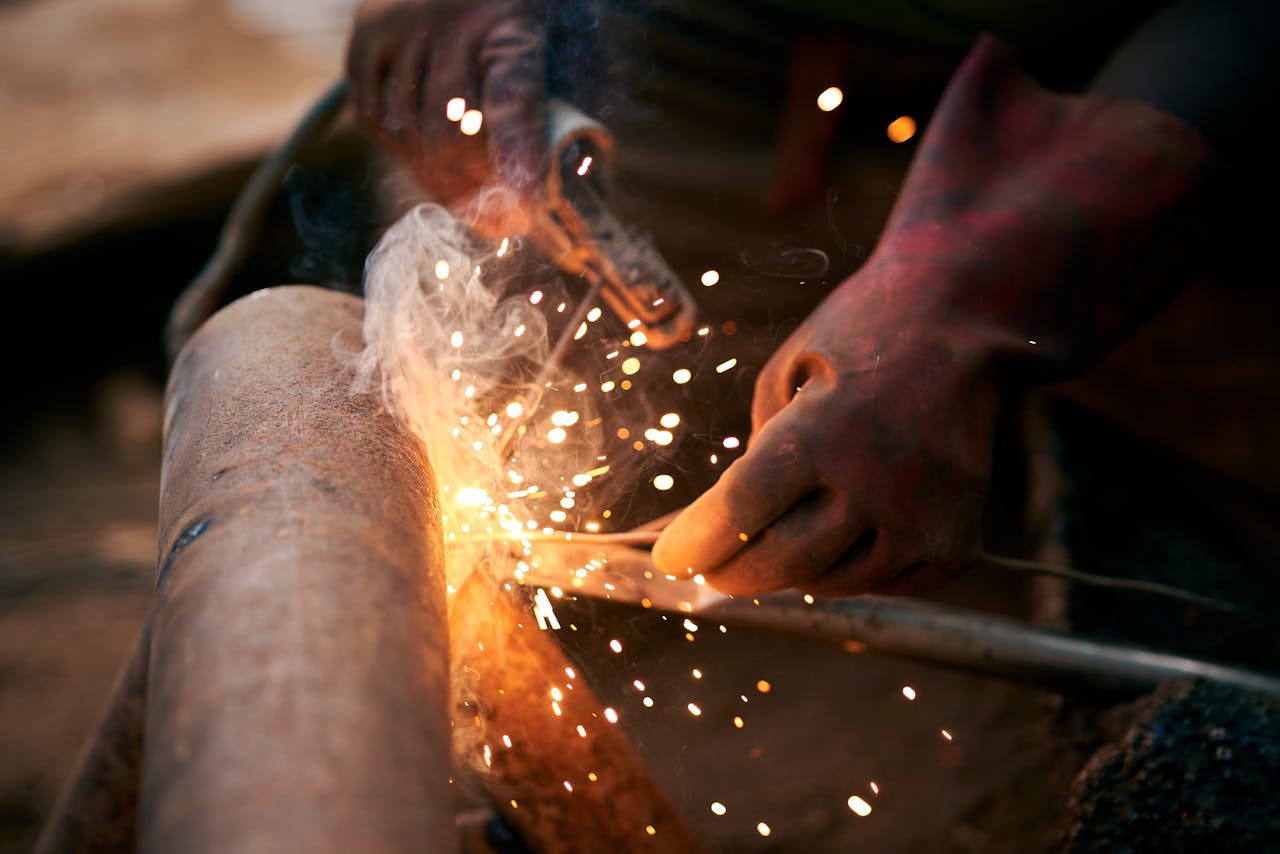 services-03 Detailed view of a welder's hands with gloves as sparks fly during welding.