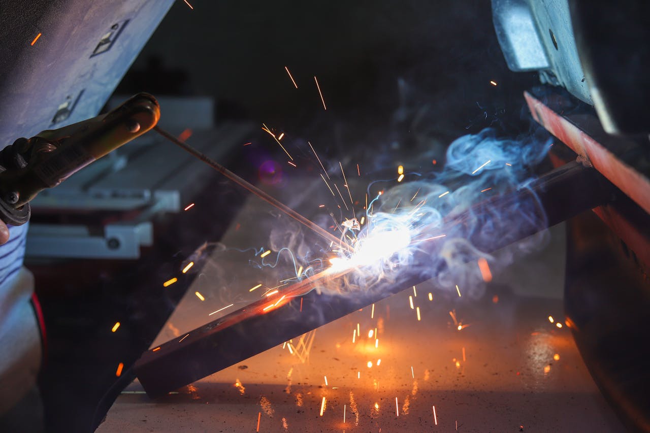 services-02 Close-up of a welder at work with sparks and smoke in an industrial setting.