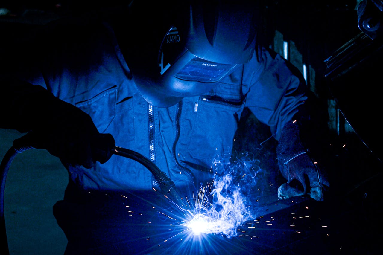 about-01 A welder using protective gear works with intense sparks flying.