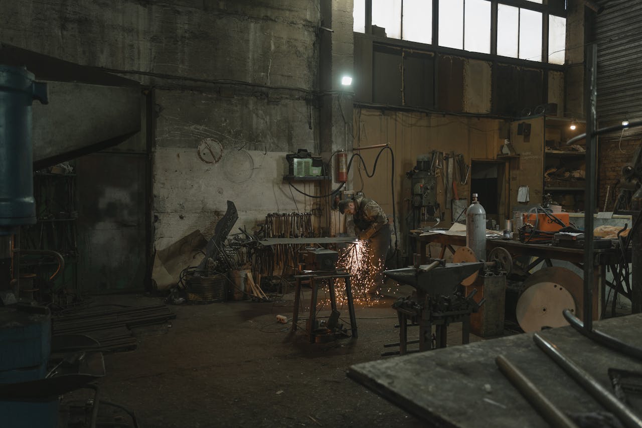 about-img A welder skillfully works with sparks flying in an industrial workshop setting.